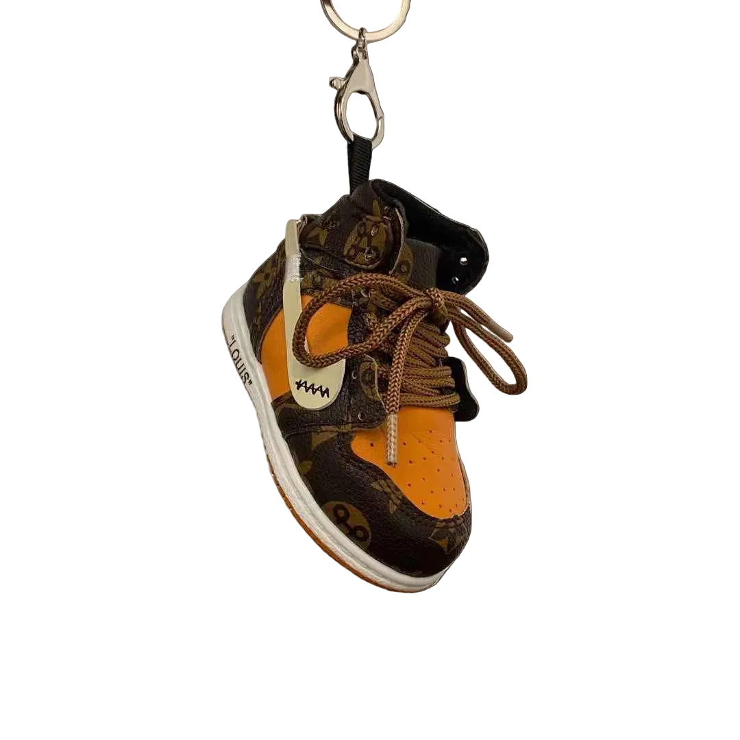 Louis Vuitton sneaker keychain on a wooden surface with a white background
